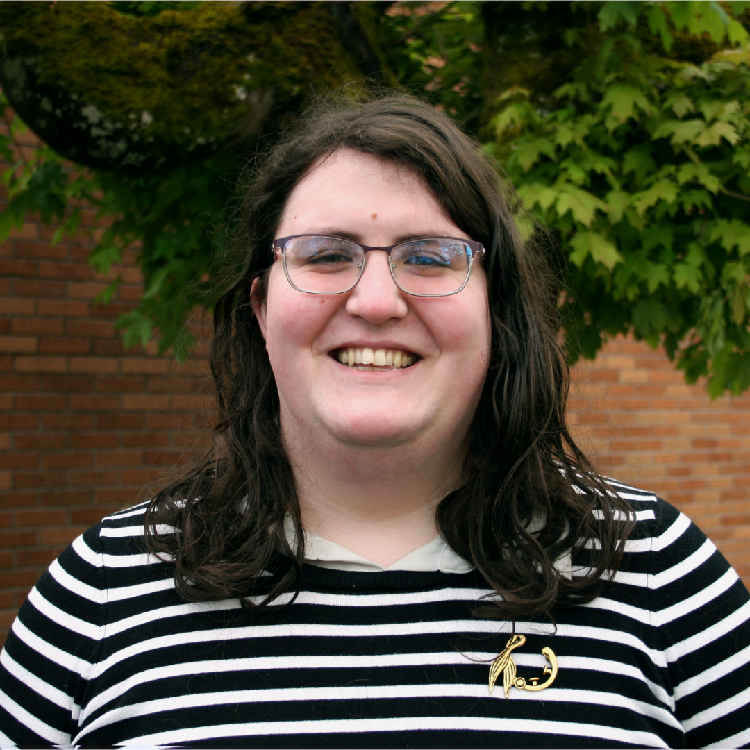 Autumn smiling in front of a tree and brick wall